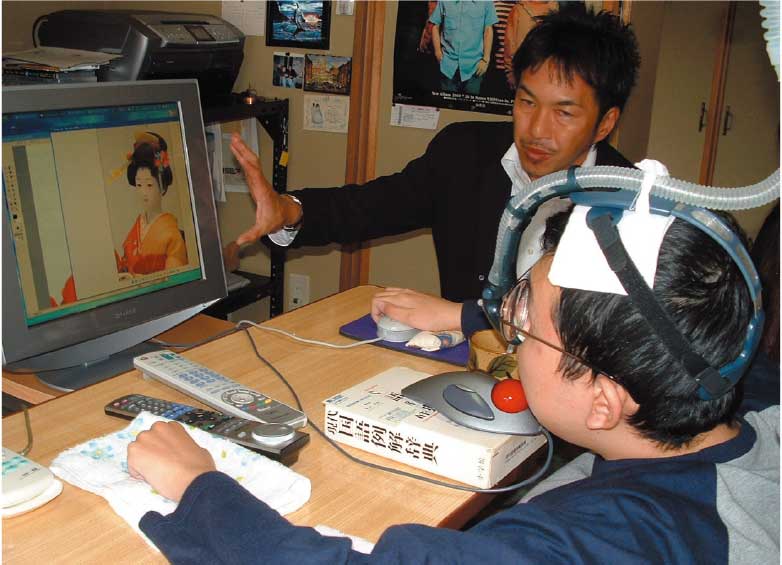 青山編集長にパソコンの画面を見せながら画像の製作工程を説明している工藤靖也さん