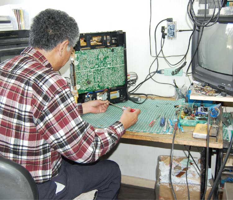 テクニカルショップイシイでテレビの修理をしている男性